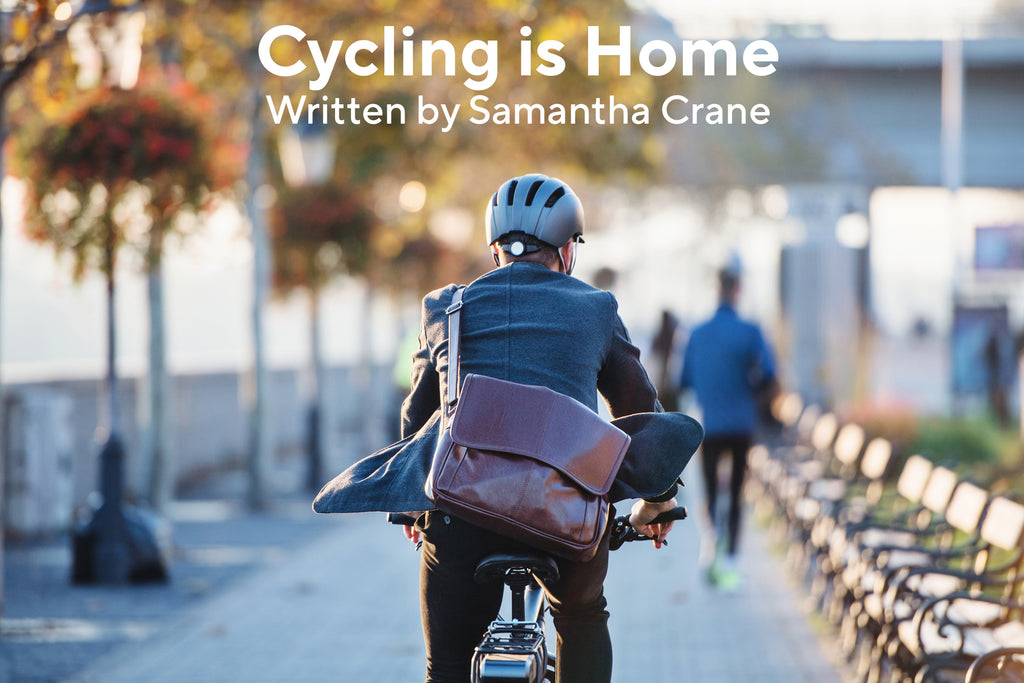 Image of a man carrying a leather bag while riding a bike wearing a helmet. Title of the blog post is "Cycling is Home", written by Samantha Crane.