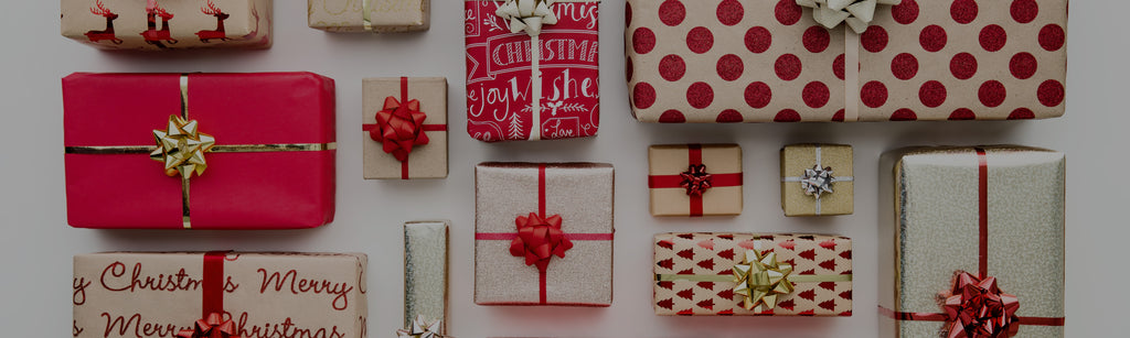 aerial view of various wrapped gifts using red, white, and gold papers on a white table