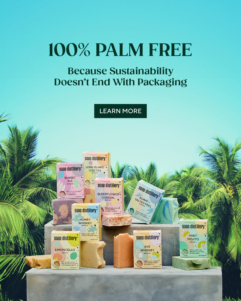 8 of our bar soaps in their colorful boxes mixed with the naked soaps on a concrete block with palm trees and a turquoise sky in the background. Text reads: 100% palm free, because sustainability doesn't end with packaging. Button to learn more.