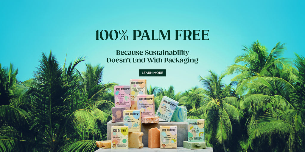 8 of our bar soaps in their colorful boxes mixed with the naked soaps on a concrete block with palm trees and a turquoise sky in the background. Text reads: 100% palm free, because sustainability doesn't end with packaging. Button to learn more.