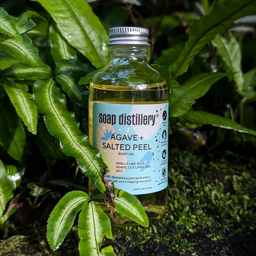 lifestyle image of the agave body oil amongst plants on a bed of moss