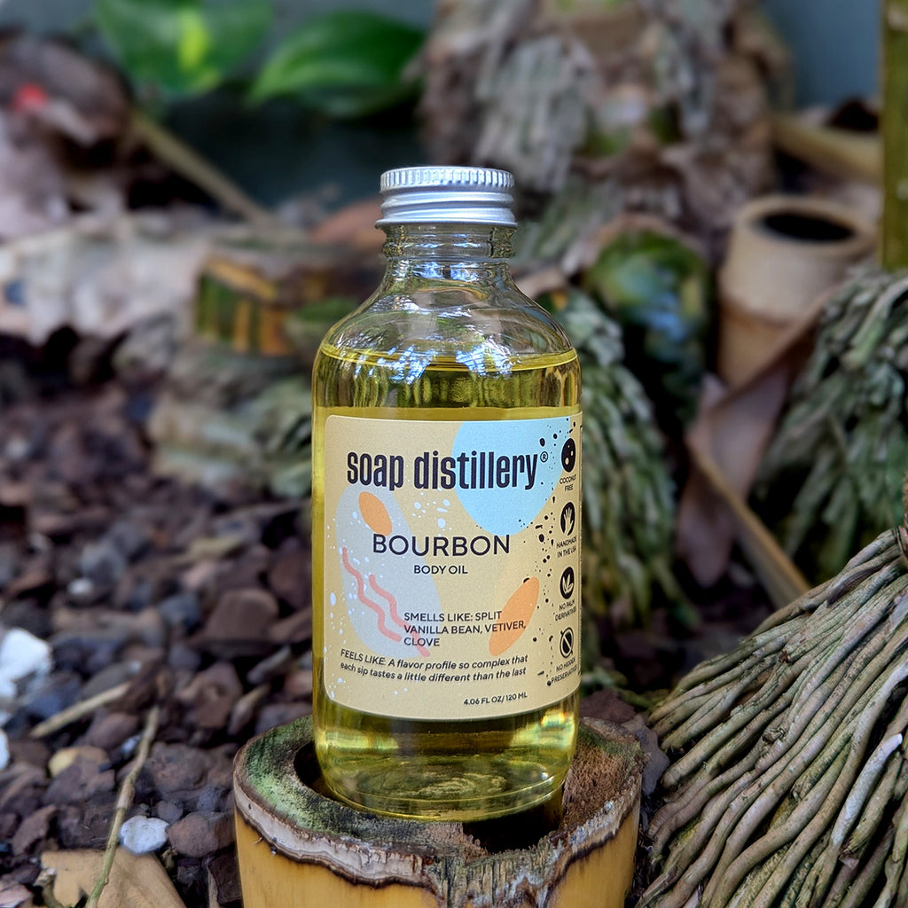 lifestyle image of the bourbon body oil amongst plants on a bamboo stump