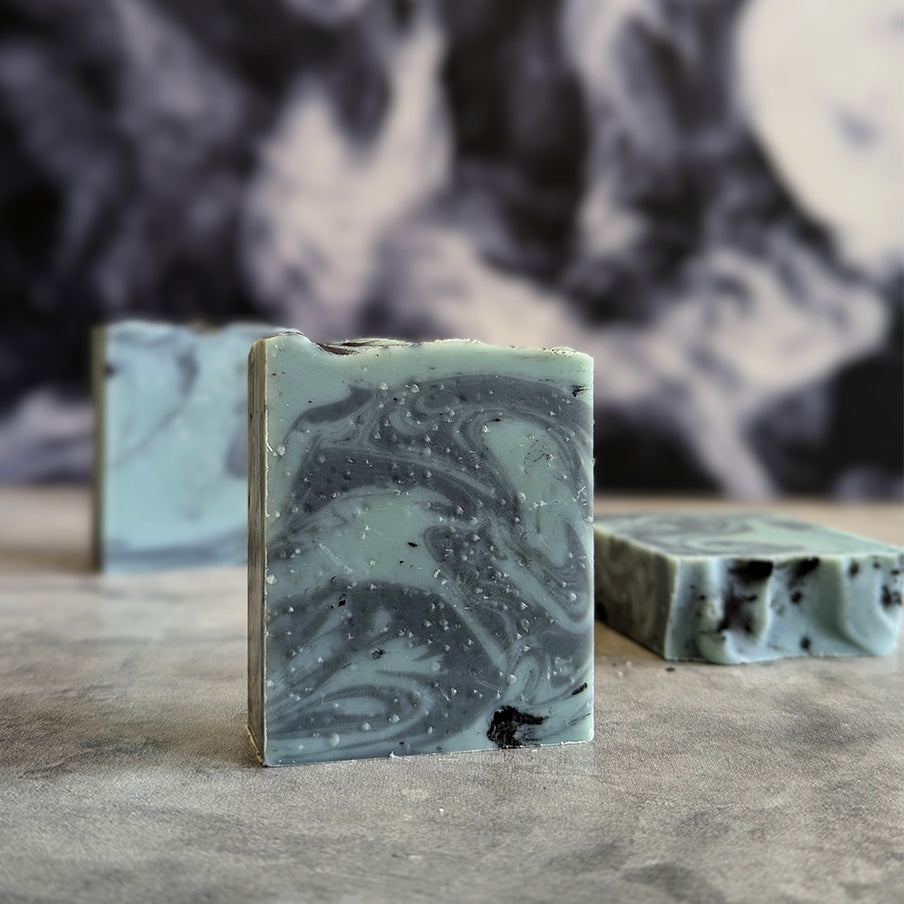 green and black swirled bar soap on a grey surface with a smoky background