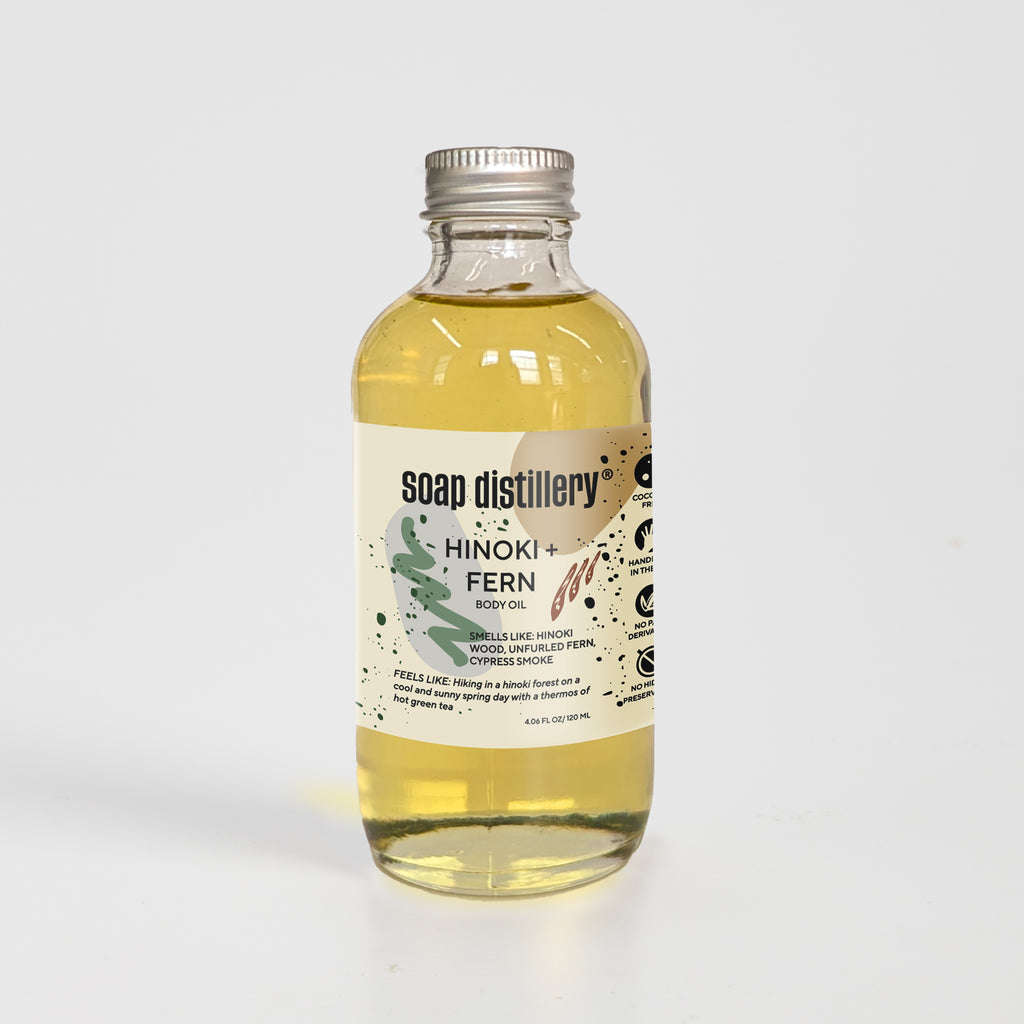 golden body oil in glass bottle with silver cap and tan colored label