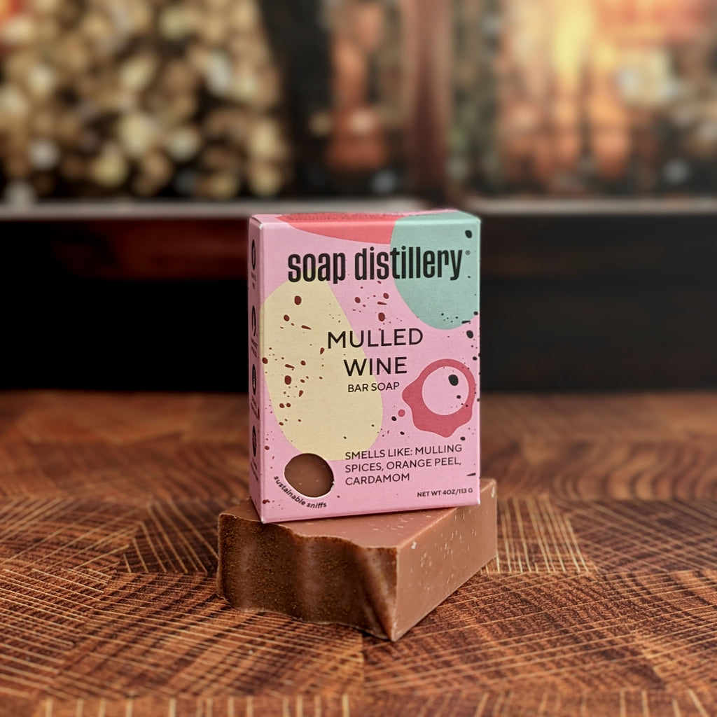 mulled wine bar soap in colorful pinkish packaging against a blurred lifestyle background of a christmas tree