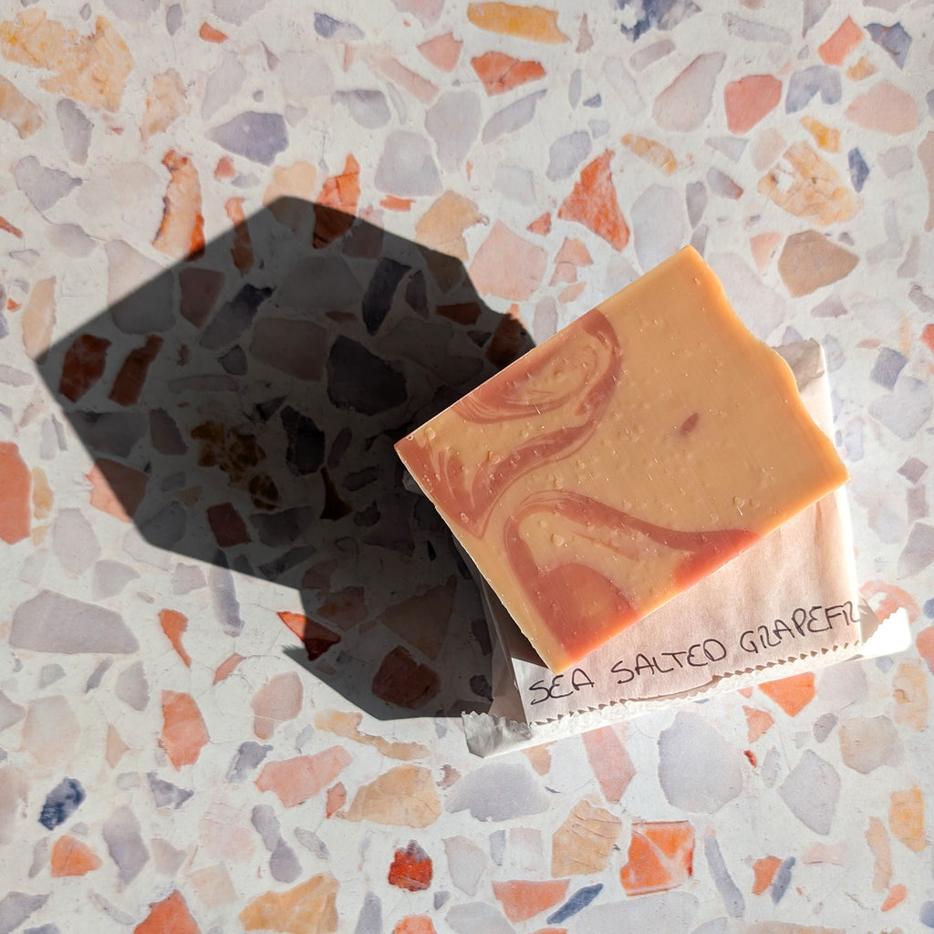 aerial shot of package free peach colored bar soap with a dark peach swirl and a strong shadow