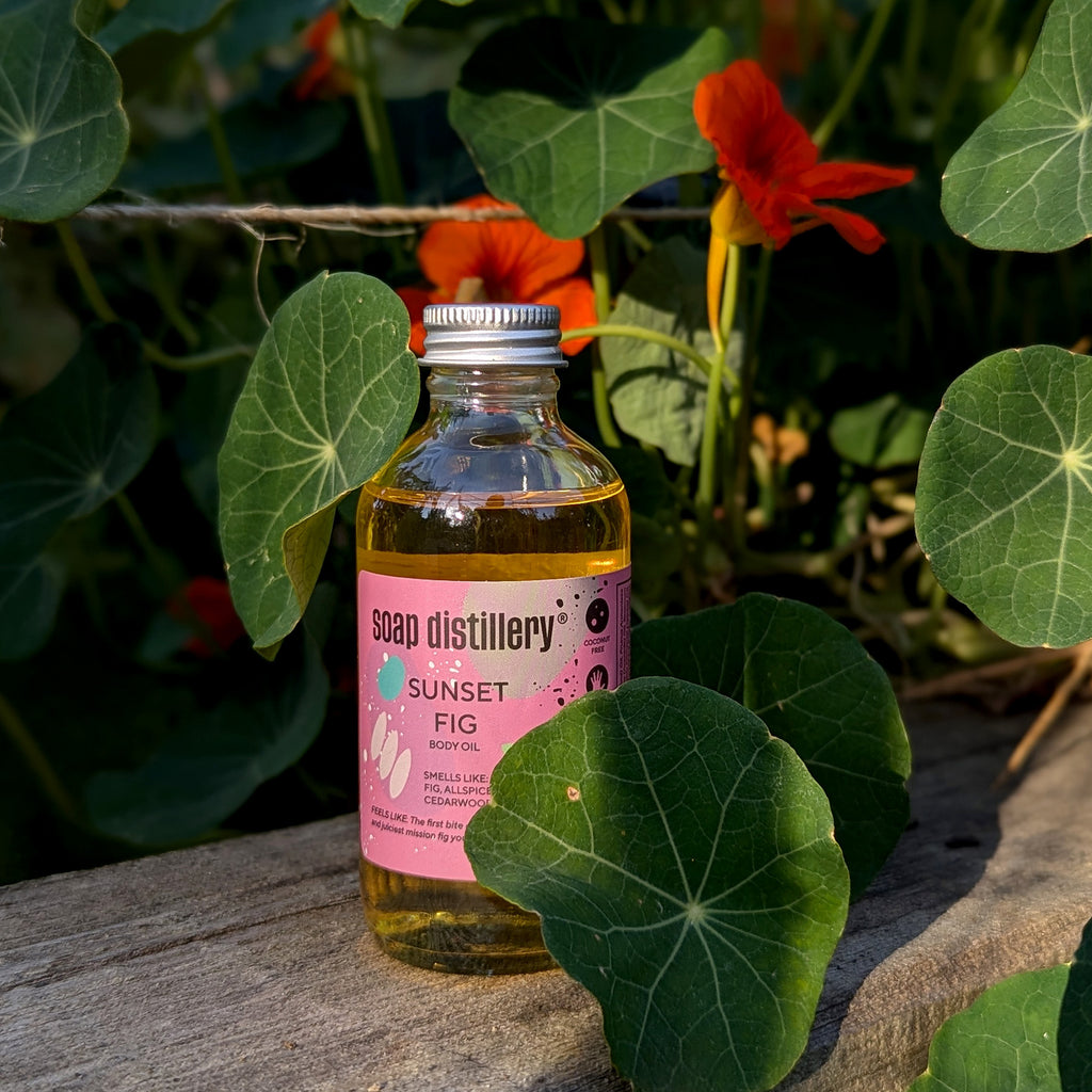 sunset fig body oil surrounded by nasturtiums