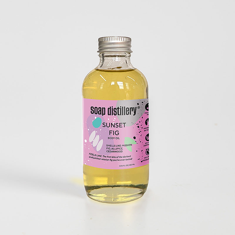 golden body oil in glass bottle with silver cap and magenta colored label