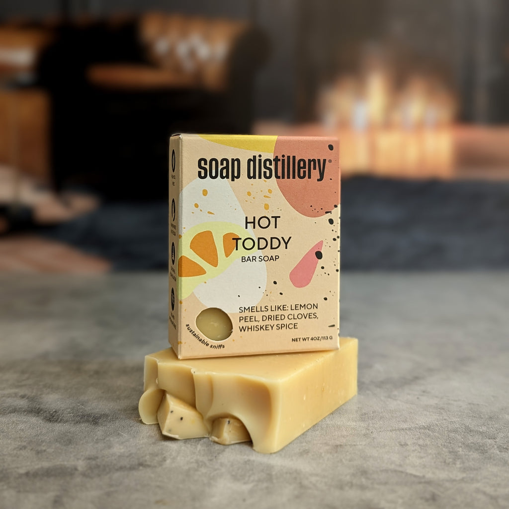 hot toddy bar soap in yellow multicolor packaging with a blurred grey background
