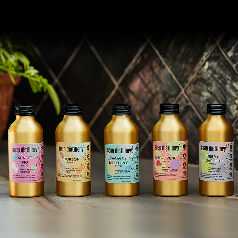 image of body oil bottles in gold anodized bottles against a black tile background in a kitchen setting