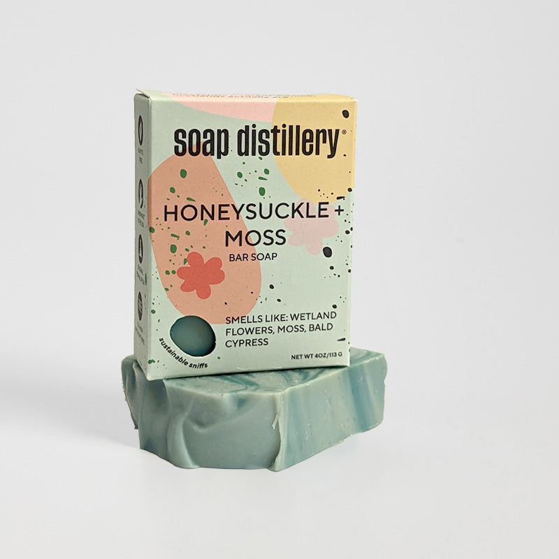 honeysuckle + moss bar soap in colorful sea foam green paperboard packaging against a light grey background.